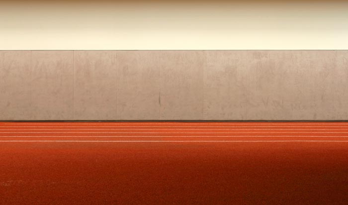 Rote Leichtathletik-Rennbahn mit grauer Wand im Hintergrund