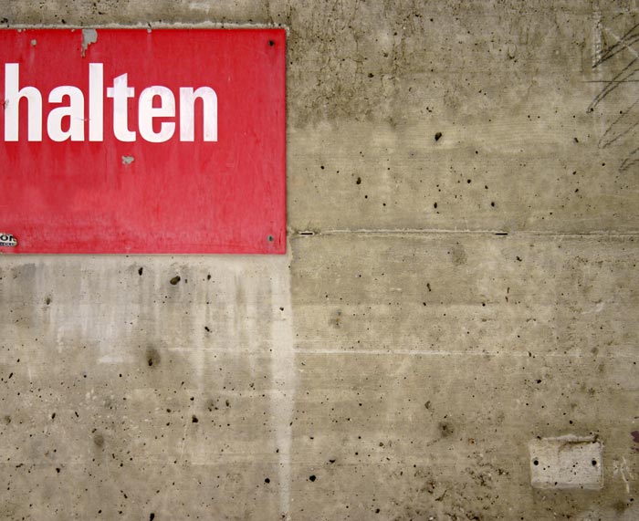 Mauer mit rotem Schild, Aufschrift “halten”